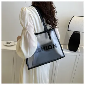 Close-up of translucent PVC tote bag with FASHION print worn by a model in a minimal setting