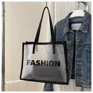 Detail of semi-transparent frosted tote bag featuring black FASHION lettering and reinforced edges