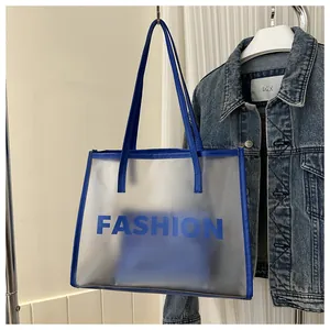 Detail of blue leather handles and frosted tote bag with Fashion text and denim backdrop