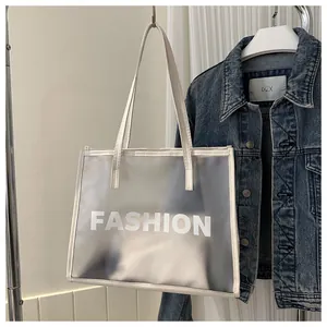 Detail of translucent white tote bag with FASHION text and leather trim on blue denim