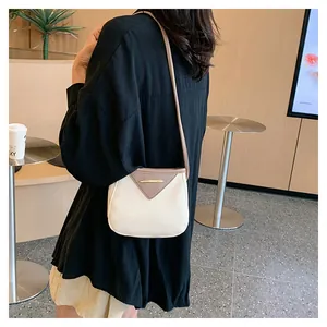 Détail d'un sac seau bicolore minimaliste avec garniture en métal doré et bandoulière