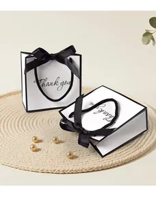 Detail of white gift paper bags featuring black bow ribbon and Thank You cursive script