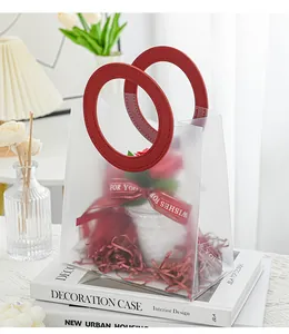 Nahaufnahme der mattierten, halbtransparenten Geschenktüte mit rotem Ringgriff und Blumen