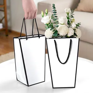 Bolsa de regalo blanca trapezoidal minimalista con bordes negros y flores frescas