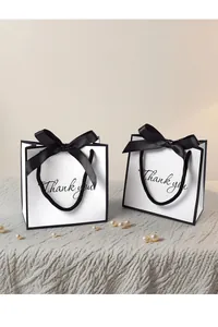 Close-up of white gift bags with black ribbon bows and Thank You cursive text