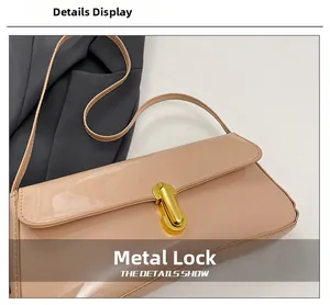 Close-up of golden metal buckle on nude apricot patent leather shoulder bag