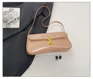 Detail of glossy beige patent leather bag with gold buckle and phone for size comparison