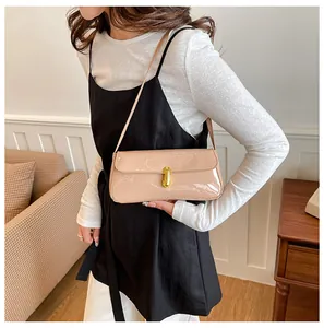 Detail of glossy beige patent leather underarm bag featuring a gold metal twist lock buckle