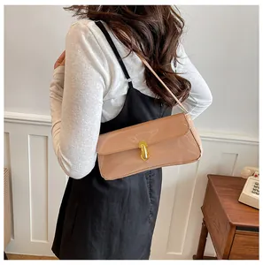 Detail of apricot patent leather baguette bag featuring a sleek gold metal buckle