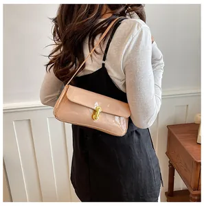 Detail of beige patent leather baguette bag featuring a gold oval twist lock and strap