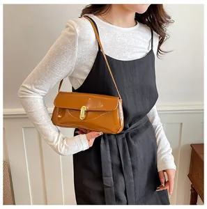 Close-up of caramel brown glossy shoulder bag with a gold metal twist-lock buckle
