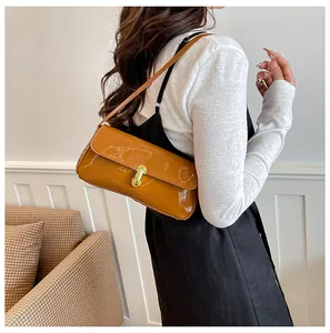 Detail of glossy mustard yellow patent leather shoulder bag with golden buckle closure