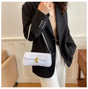 Detail view of white patent leather shoulder bag with gold clasp on female model