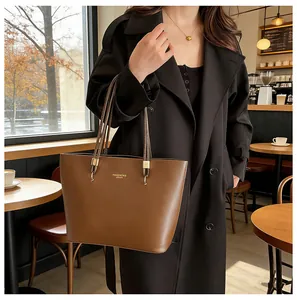 Detail der karamellbraunen Leder-Shopper mit feiner Goldprägung und Metallschließe