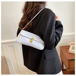Detail of a retro patent leather baguette bag with a gold lock worn on the shoulder