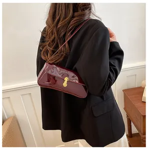 Detail view of burgundy patent leather shoulder bag with gold metal twist lock closure