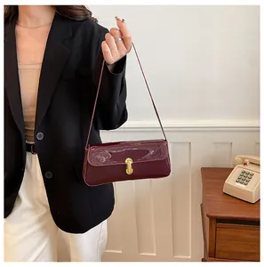 Detail shot of a burgundy patent leather shoulder bag with a sleek gold metal lock