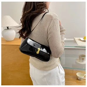 Close-up of black patent leather baguette bag with a gold oval clasp and sleek strap
