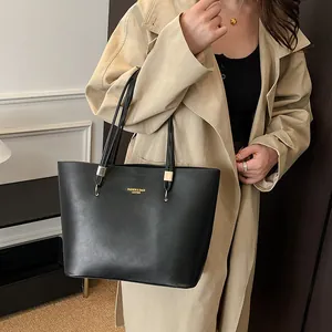 Minimalistische schwarze Leder-Einkaufstasche mit Goldaufdruck auf der Schulter mit Trenchcoat