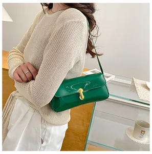 Close-up of green patent leather baguette bag with golden U-shaped buckle closure
