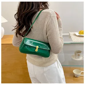 Detail view of emerald green patent leather shoulder bag with a gold metal lock buckle
