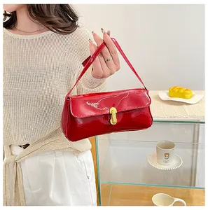 Detail of red patent leather shoulder bag with gold clasp shown in a lifestyle setting