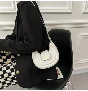 Dettaglio borsa a sella a mezzaluna bianca con trama a pieghe e scritta Classic sulla patta