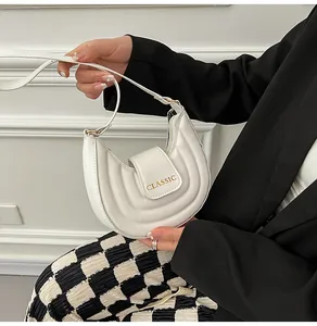 Dettaglio della borsa a sella trapuntata bianca a mezzaluna con testo Classic dorato