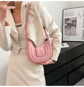 Dettaglio della borsa a sella rosa a mezzaluna con scritta Classic dorata in pelle PU