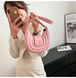 Dettaglio borsa a sella rosa chiaro con trama plissettata e scritta Classic sulla patta
