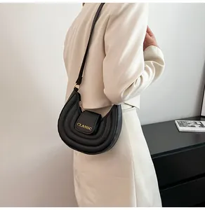 Dettaglio borsa a sella trapuntata nera con scritta Classic dorata e tracolla sottile