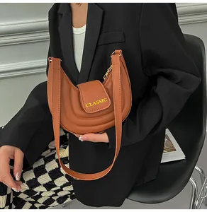 Dettaglio borsa a sella marrone con scritta CLASSIC e cuciture su pelle PU