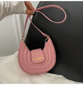 Dettaglio della borsa a sella rosa con scritta CLASSIC dorata e chiusura a patta magnetica
