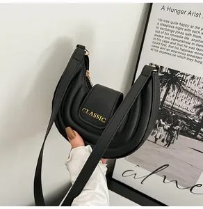 Dettaglio borsa a sella nera trapuntata con logo CLASSIC dorato inciso sopra