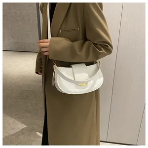 Close-up of white crescent saddle bag featuring gold metal buckle and smooth leather