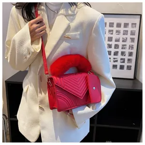 Detail of red crossbody bag with V-shaped stitching and plush faux fur handle