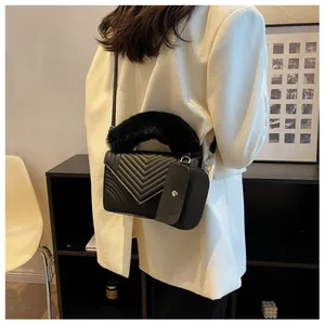 Detail of black quilted leather handbag with plush faux fur handle and mini pouch charm