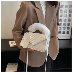 White quilted handbag with faux fur handle and small coin purse shown on a brown blazer