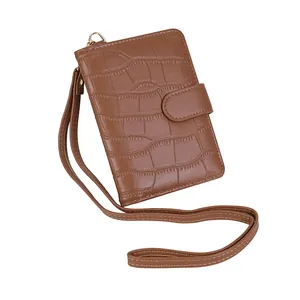 Detailed view of crocodile embossed leather texture on brown passport holder with neck strap