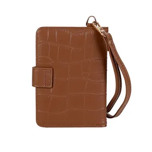 Detailed close-up of brown crocodile texture leather passport holder with wrist strap