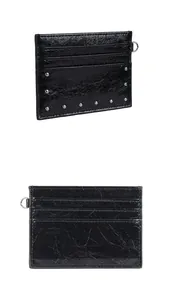 Detail of black cracked leather card holder featuring silver studs and metal D-ring attachment