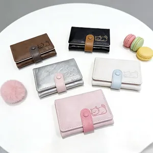 Top view of compact cat wallets in five colors on a decorative tabletop with macaroons