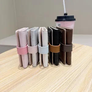 Detailed view of trifold cat wallets in five colors on a wooden table surface