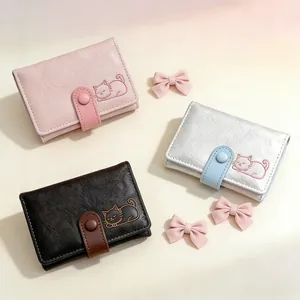 Three cute textured faux leather wallets with embossed cat patterns in pink, silver and brown
