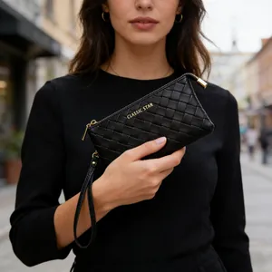 Close-up of black quilted woven clutch bag with gold zipper and wrist strap detail