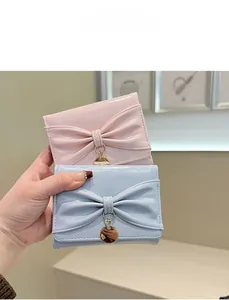 Vue détaillée de portefeuilles en cuir verni rose et bleu avec nœud et pendentif doré