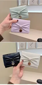 Détail de portefeuilles pliants avec nœud en vert pastel, violet, noir et beige crème