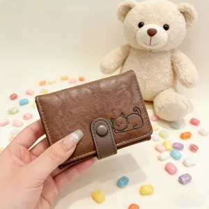 Close-up of brown textured leather wallet featuring an embossed cat face and button clasp