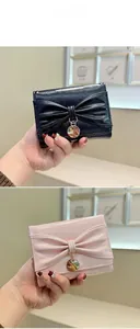 Détail de petits portefeuilles en cuir brillant avec nœud et pendentif doré en rose et noir