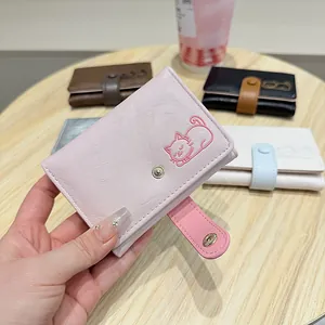 Close-up of pink trifold wallet featuring cute embroidered cat pattern and snap closure